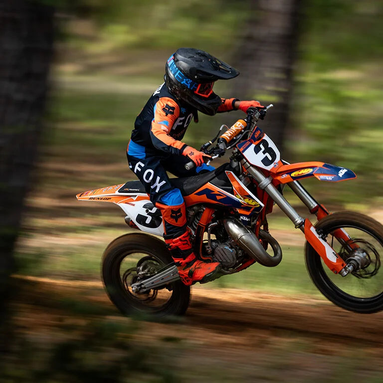 Youth rider in Fox gear riding through woods