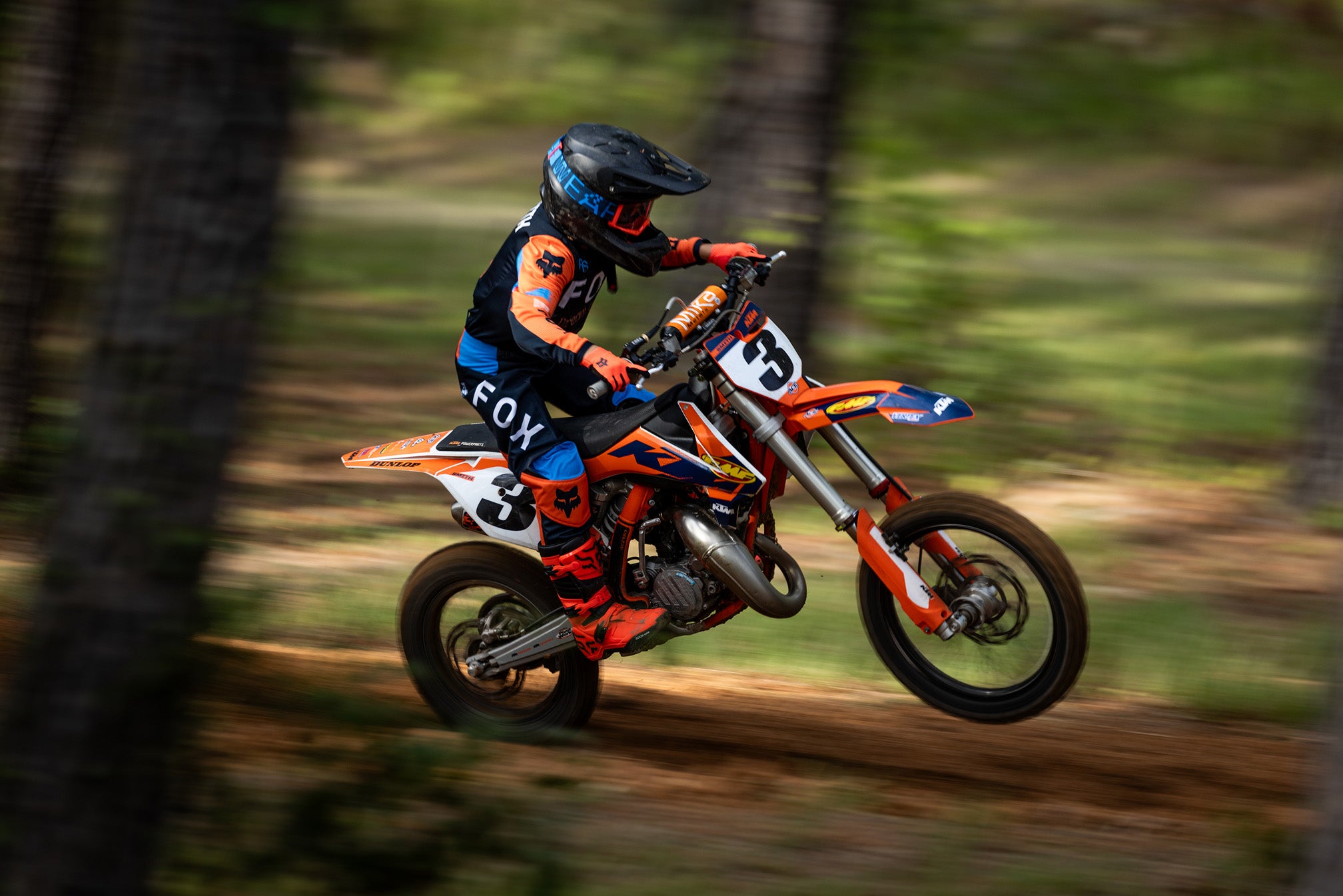 Youth rider in Fox Racing Race Spec Gear wheeling on woods trail