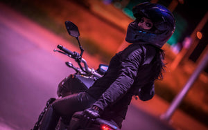 Rider in Helmet looking back at camera under city lights