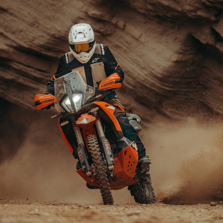 Alpinestars Andes V4 Drystar Jacket Walnut Mastic/Black - Lifestyle Shot of Rider in Jacket Riding through Canyon on Orange Dual Sport Motorcycle