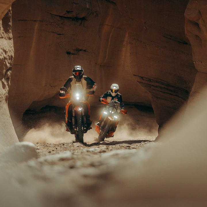 Alpinestars Andes V4 Drystar Jacket Walnut Mastic/Black - Lifestyle Shot of Two Riders in Jackets Riding Through Canyon on Orange Dual Sport Motorcycles