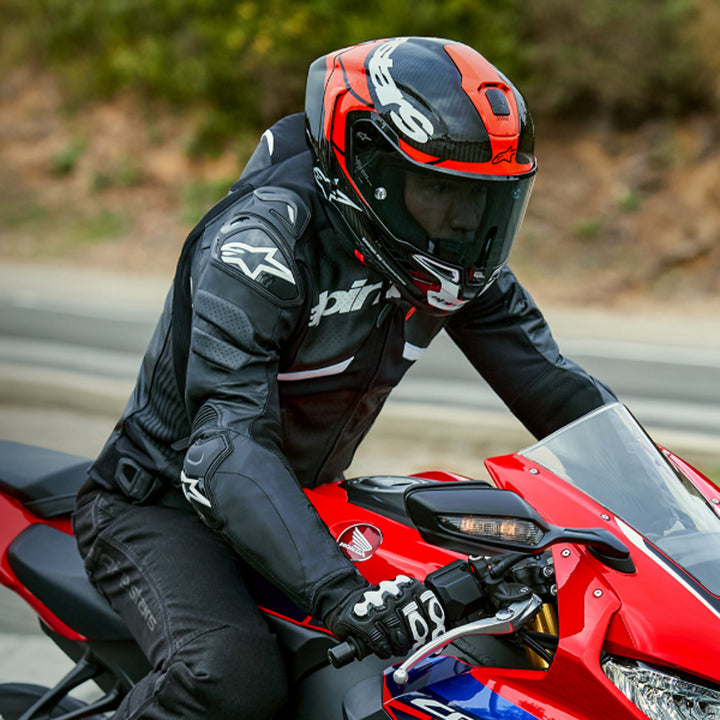 Alpinestars Supertech R10 Element Helmet Carbon/Red/White - Lifestyle Shot of Rider Wearing Helmet on Red Sport Motorcycle