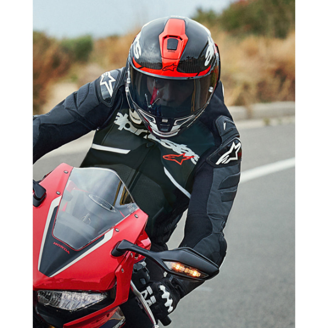Alpinestars Supertech R10 Element Helmet Carbon/Red/White - Lifestyle head-on shot of rider wearing helmet coming through turn on red sport motorcycle