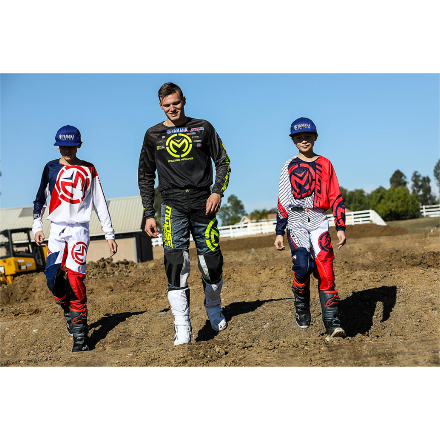 Alpinestars Youth Tech 7S Boots - Lifestyle of one adult and two youth riders walking in shoes across muddy track