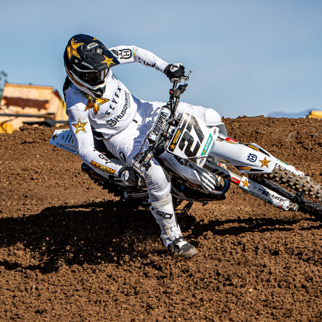Motocross rider in full gear taking turn on dirt track