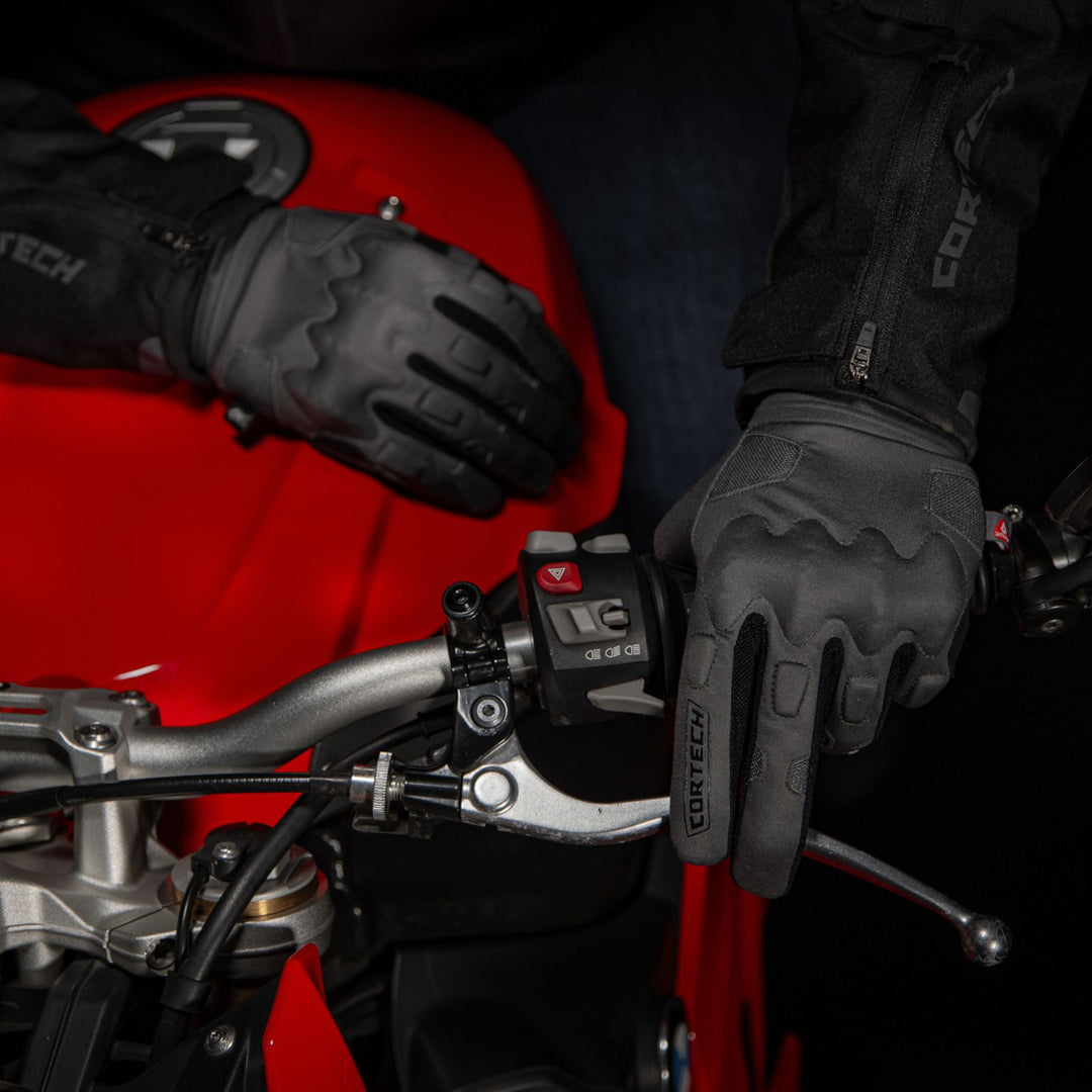 Cortech Lite Gloves Black/Black - Lifestyle Shot of one gloved hand on grip and clutch lever and other gloved hand resting on tank of red motorcycle