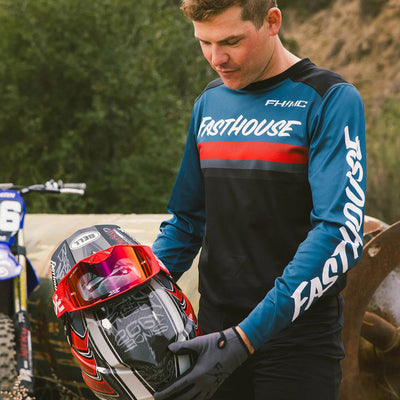 Fasthouse Carbon Force Jersey Teal - Lifestyle of Rider Wearing Jersey While Picking Up Helmet