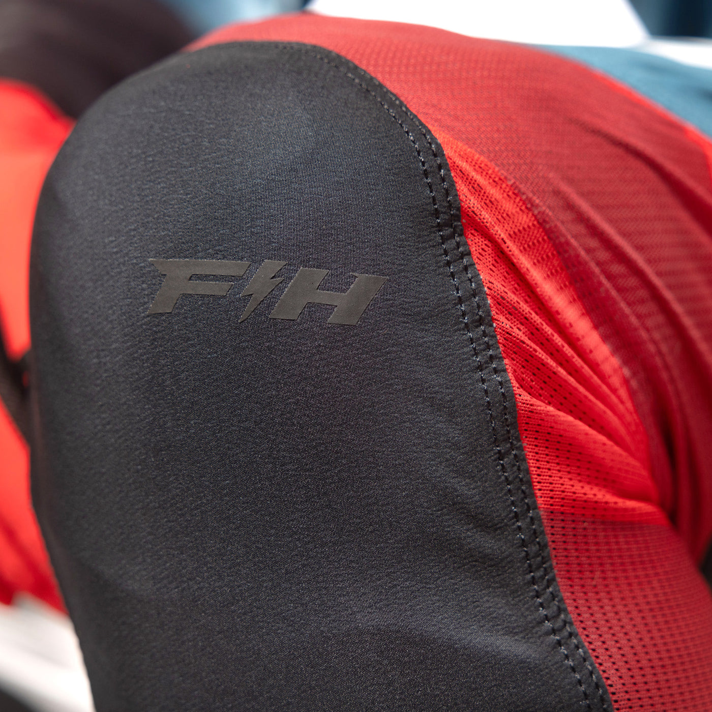 Fasthouse Helix Podium Pant Red/Black/Teal - Close-Up of Knee Logo