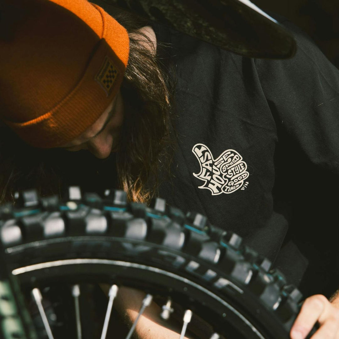 Fasthouse Satisfaction SS Tee Black - Lifestyle Close-Up of Person Wearing Shirt while Checking Tire