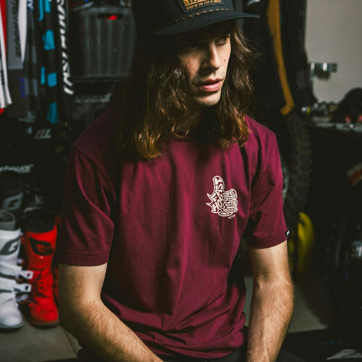 Fasthouse Satisfaction SS Tee Maroon - Lifestyle of Man Wearing Shirt while sitting in garage