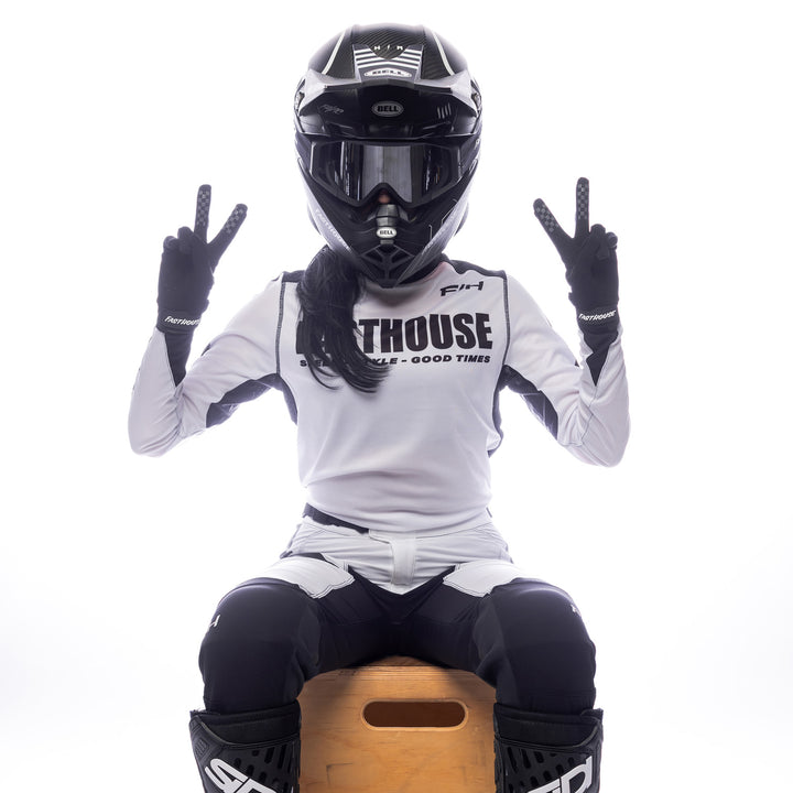 Fasthouse Women's Elrod Storm Jersey White/Black - Front View of Model Sitting While Wearing Jersey and Throwing Peace Signs