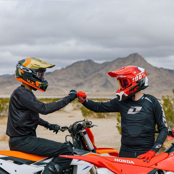 HJC C50 Primal Helmet MC-1 and MC-6HSF - Lifestyle Shot of Two Dirt Bike Riders Wearing Helmets While Fist-Bumping