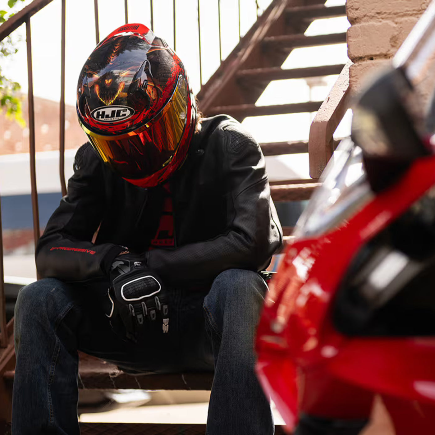 HJC RPHA 12 Diablo Blizzard Helmet MC-1 - Lifestyle of Rider Wearing Helmet while Sitting on Metal Staircase