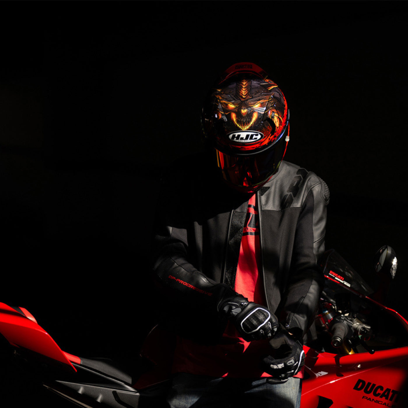 HJC RPHA 12 Diablo Blizzard Helmet MC-1 - Lifestyle of Rider Wearing Helmet while putting on gloves, leaning against red sport motorcycle