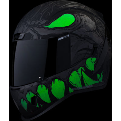 ICON Airform Manik'RR MIPS Helmet Dark Black - Front Left Side View with Dark Studio Background and Glow-in-the-Dark Graphics