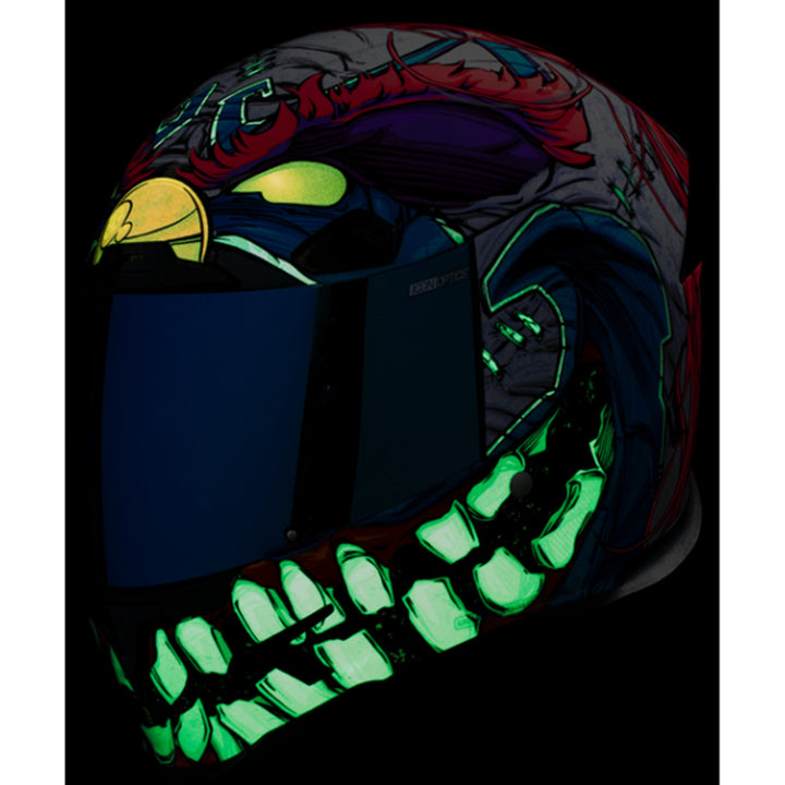 ICON Airframe Pro Krazy Klown 2 Helmet Pink - Front Left Side View with Dark Studio Background and Glow-in-the-Dark Graphics