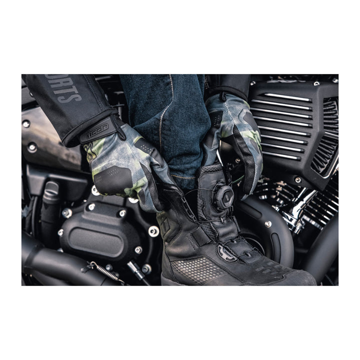 ICON Stormhawk Boots Black - Lifestyle Close-Up of Rider Reaching Down to Put On Boot