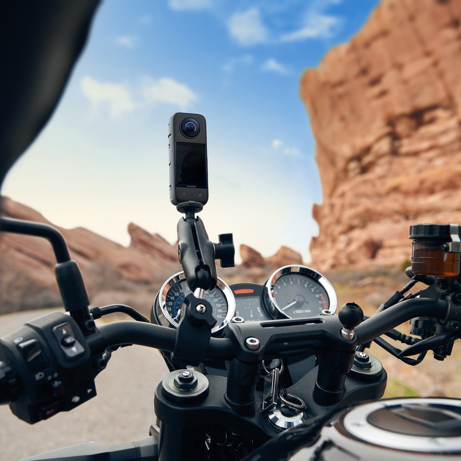 Lifestyle Close-Up of Motorcycle Handlebars with Insta360 X3 Attached and Aiming Forward Along Canyon Road
