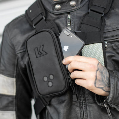 Kriega Harness Pocket XL Left - Close-Up of Model Pulling Out Phone from Pocket Attached to Right Backpack Strap for Left-Handed Access