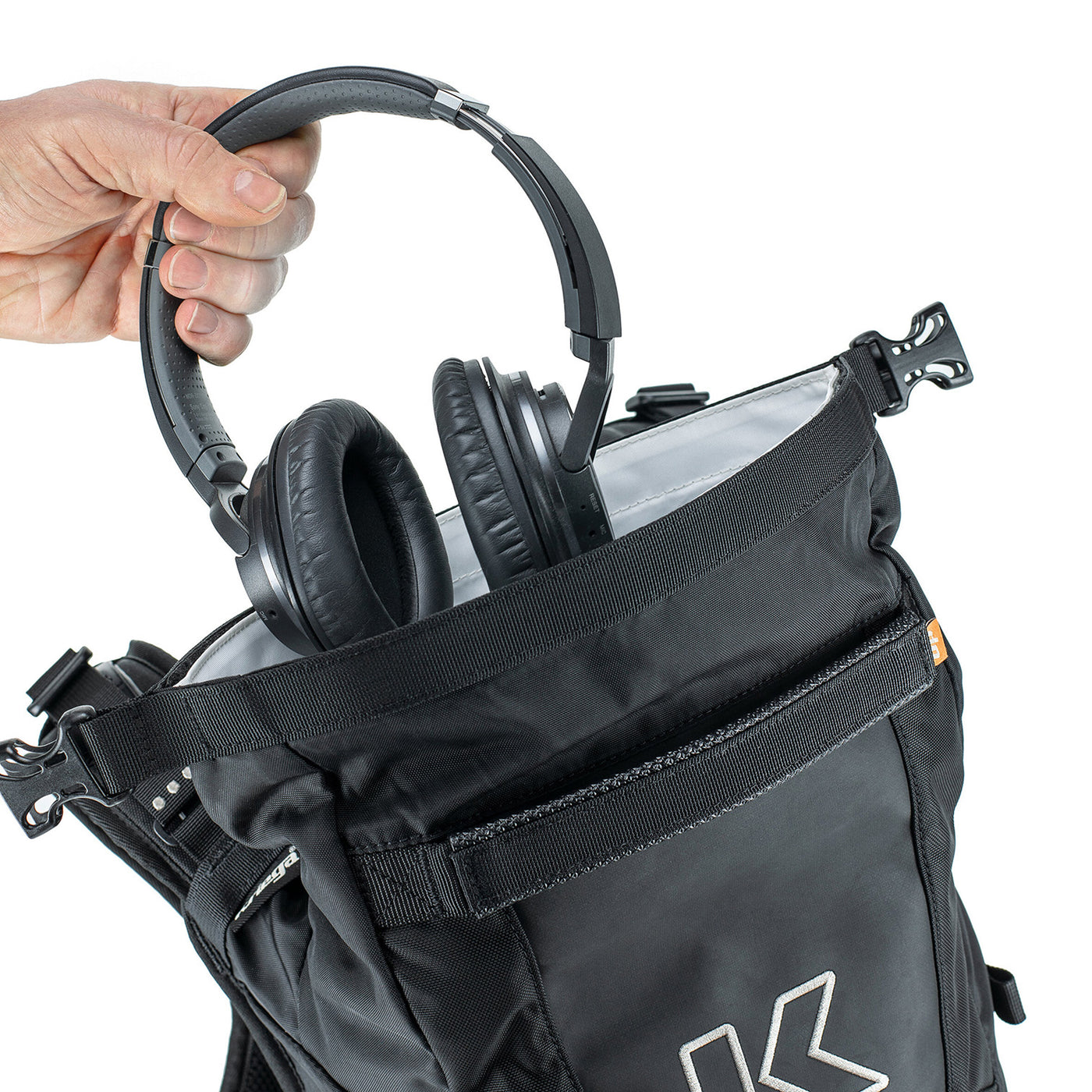 Kriega R16 Backpack - Close-Up of Model Placing Headphones into Open Top Section