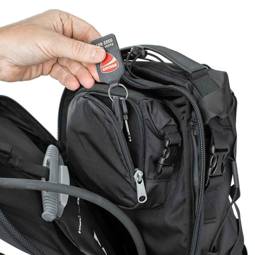 Kriega Trail 18 Adventure Backpack Black - Close-Up of Model Pulling Keys out of Zippered Pocket in Mid Section