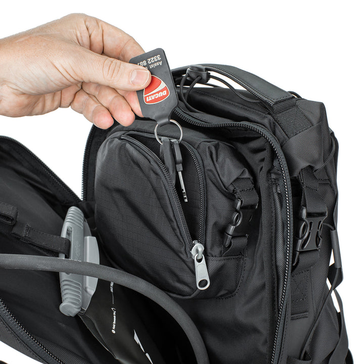 Kriega Trail 18 Adventure Backpack Black - Close-Up of Model Pulling Keys out of Zippered Pocket in Mid Section