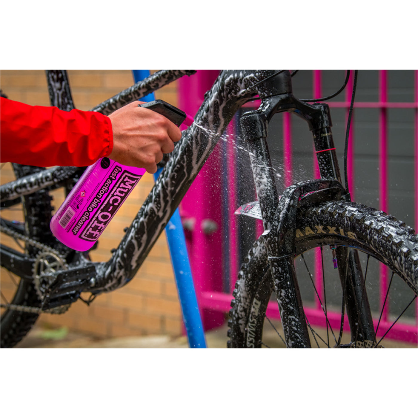 Muc-Off Punk Powder Concentrated Cleaner Refill - Lifestyle Close-Up of Model Spraying Cleaner on Bicycle