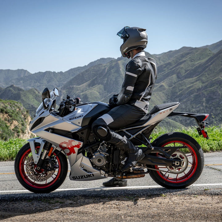 Noru Twenty-Eight 1-Piece Race Suit Black/White - Lifestyle of Model Wearing Suit on parked silver motorcycle, looking over mountain scape