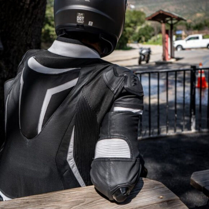Noru Twenty-Eight 1-Piece Race Suit Black/White - Lifestyle Shot from Rear of Rider in Suit sitting at Picnic Table