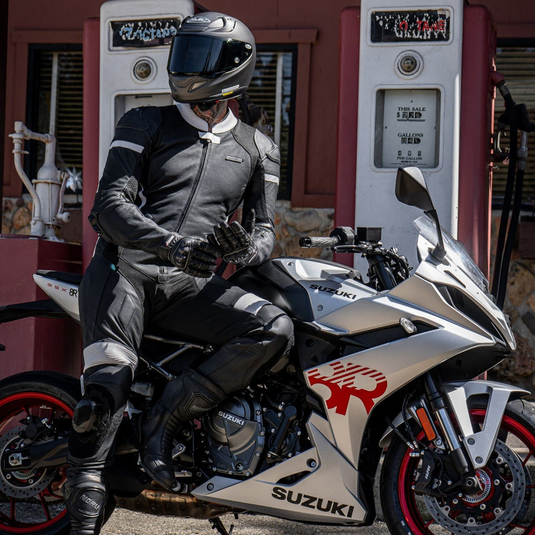 Noru Twenty-Eight 1-Piece Race Suit Black/White - Lifestyle Shot of Rider in Suit Leaning on Silver Motorcycle at Gas Station
