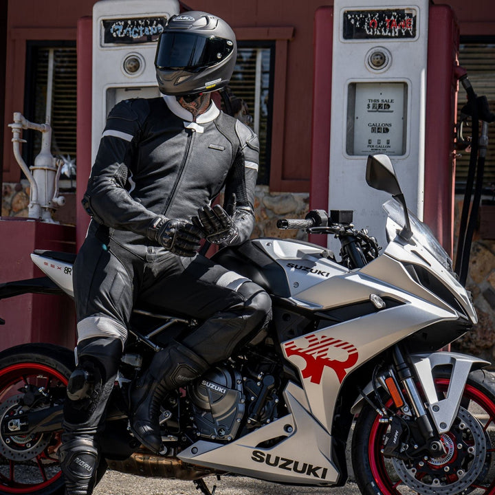 Noru Twenty-Eight 1-Piece Race Suit Black/White - Lifestyle Shot of Rider in Suit Leaning on Silver Motorcycle at Gas Station