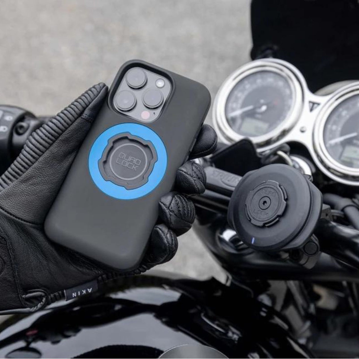 Quad Lock Phone Case - iPhone 16 Series MAG - Lifestyle Shot of gloved hand holding case above motorcycle handlebar set-up