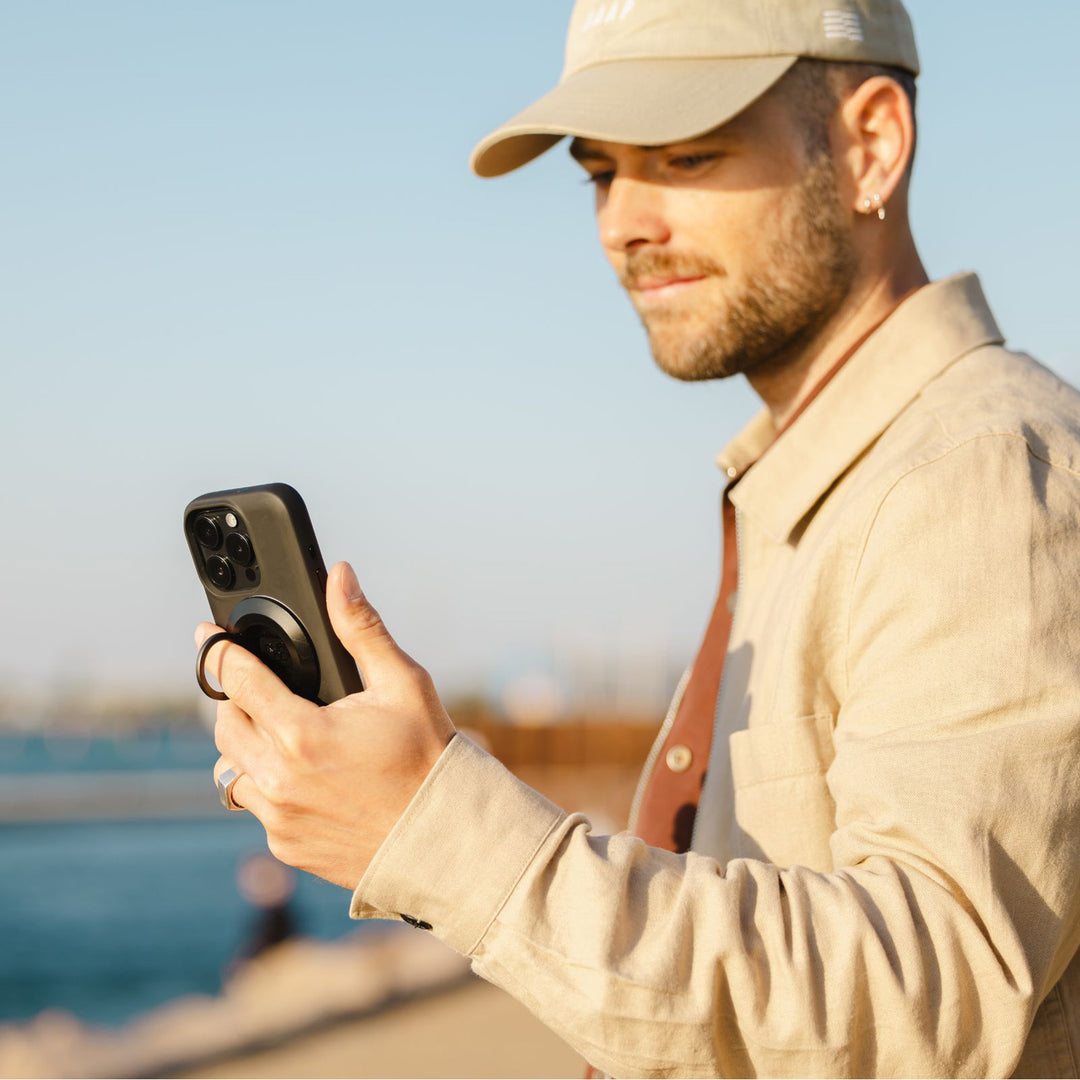 Quad Lock MAG Phone Ring Grip/Stand/Bottle Opener - Lifestyle of User Looking at Phone with Finger through Ring Grip