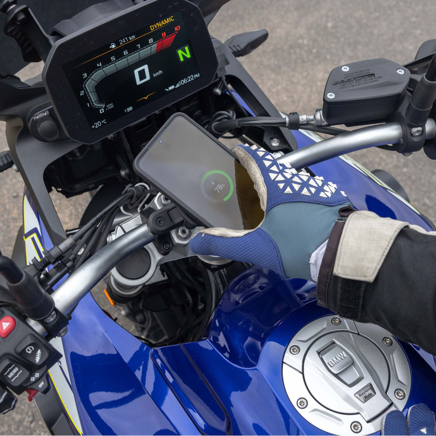 Quad Lock Motorcycle Handlebar Mount Pro - Lifestyle Shot of Rider locking phone onto handlebar mount set-up