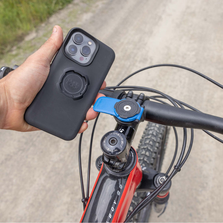 Quad Lock Out Front Mount - Lifestyle Close-Up of Rider Lining Up Phone Case with Head Lever on Mount