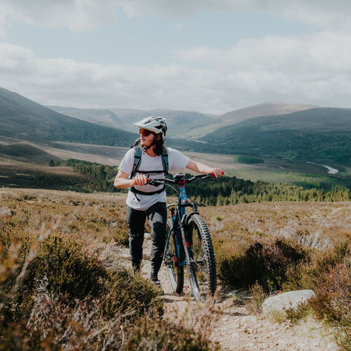Quad Lock Out Front Mount Pro - Lifestyle Wide Shot of Cyclist Walking Bicycle Up Hill Trail