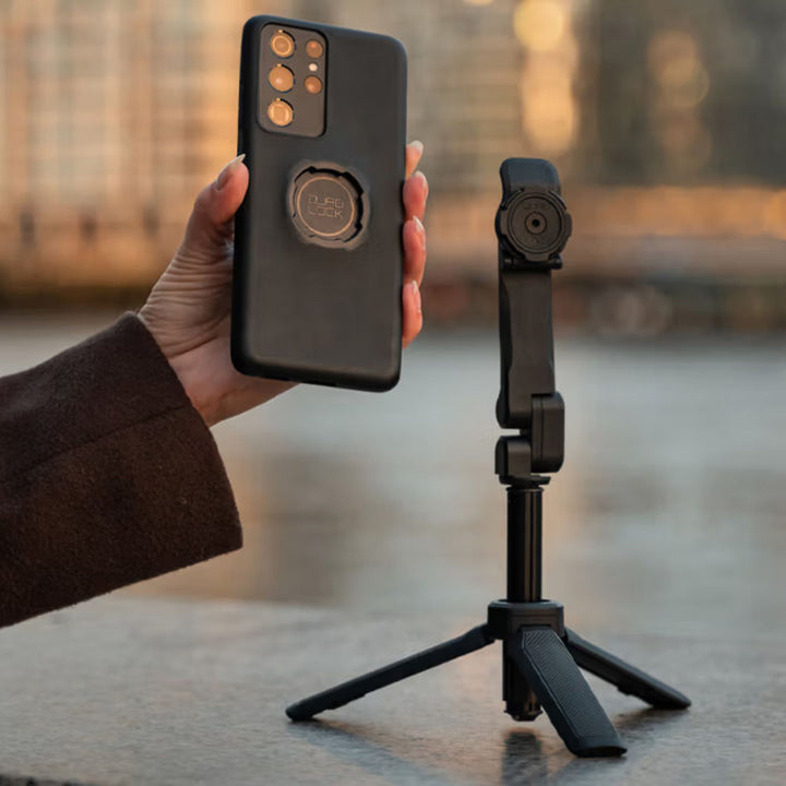Quad Lock Phone Case - Samsung Galaxy S25 Series - Lifestyle Close-Up of Model Holding Phone with Case next to Tripod