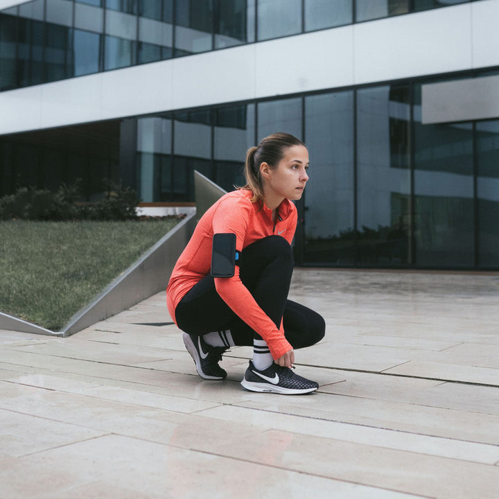 Quad Lock Sports Armband - Lifestyle of Jogger Tying Shoe with Phone on Armband