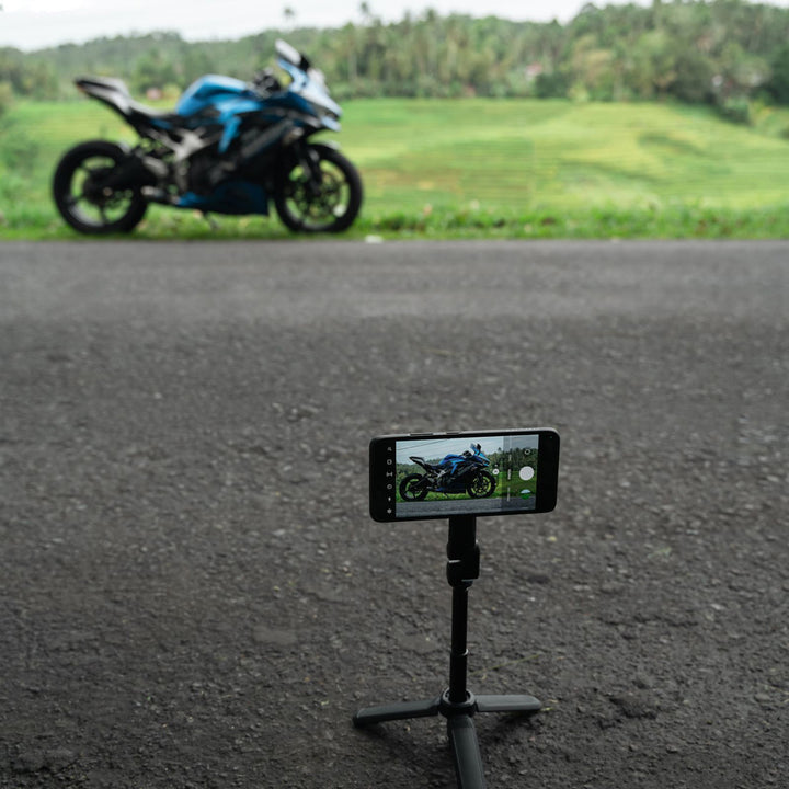 Quad Lock Tripod/Selfie Stick - Lifestyle of Phone on Extended Tripod Set to Take Picture of Motorcycle