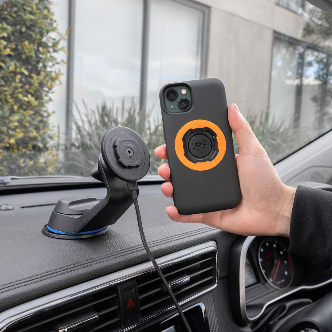 Quad Lock Windscreen/Dash Car Mount - Lifestyle of Driver Lining Up Phone Case with Charging Head on Dashboard Mount