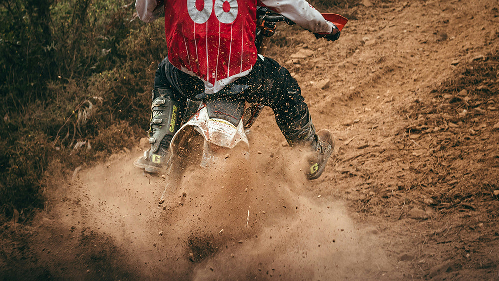 Action Shot of Dirt Rider Turning through trail, kicking dirt and roost behind at camera