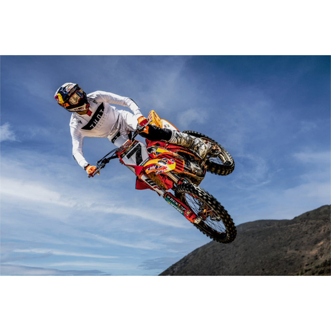 THOR SPORTMODE Rogue Jersey White/Orange - Lifestyle of Rider Wearing Jersey While Catching Air on Red Dirt Bike