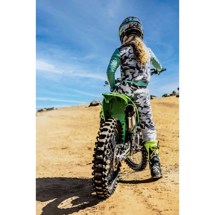 THOR Women's SPORTMODE Shadow Pants Teal - Lifestyle of Rider Wearing Pants on Green Dirt Bike