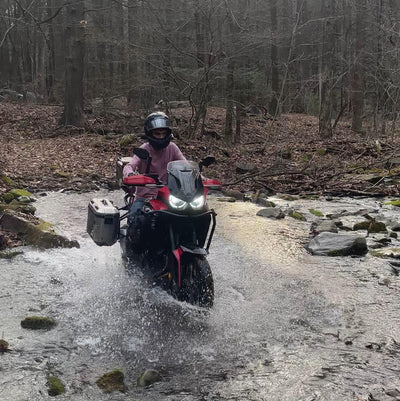 Our Expert, Caleb, on his 2022 Honda Africa Twin riding through a creek in the woods