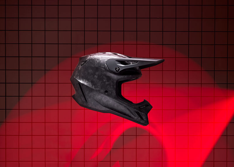 stylized stock image of Fox Racing V3 RS Carbon Helmet, suspended in red lighting against tiled background