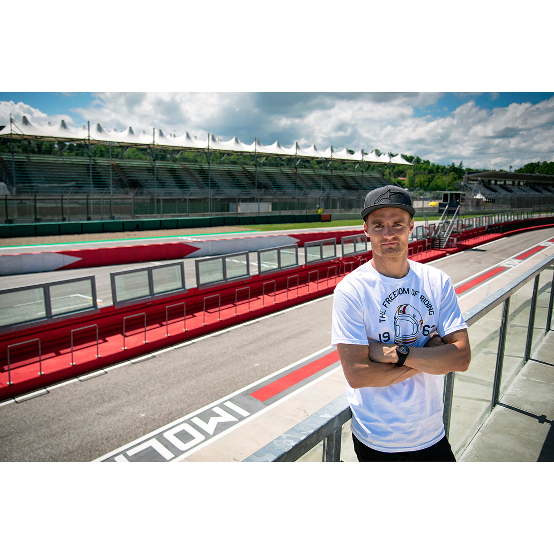 Alpinestars Ageless Curve Hat Heather Charcoal/Black - Lifestyle of Model Wearing Hat while Posing Trackside