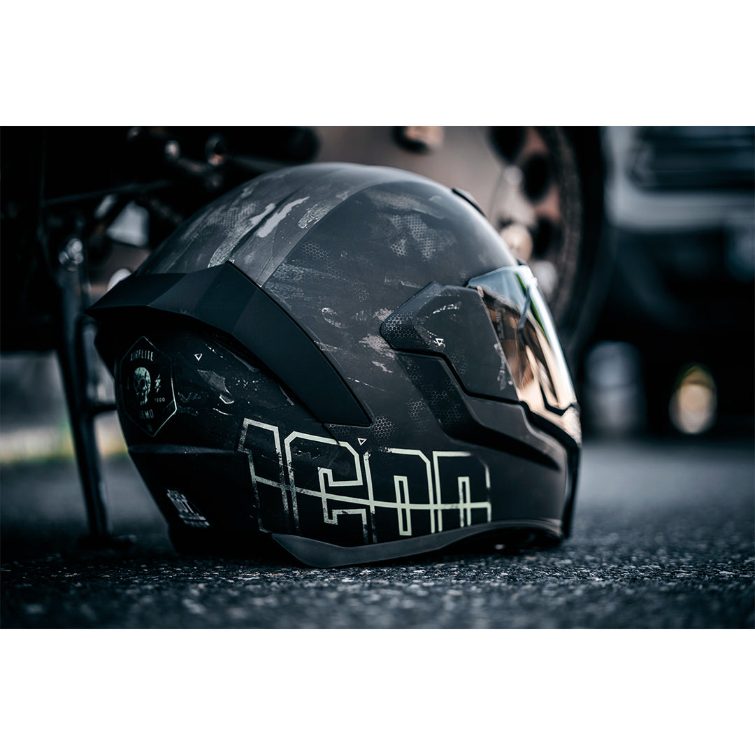 ICON Airflite™ Demo MIPS® Helmet Black - Lifestyle shot of Helmet Resting on Ground Next to Motorcycle