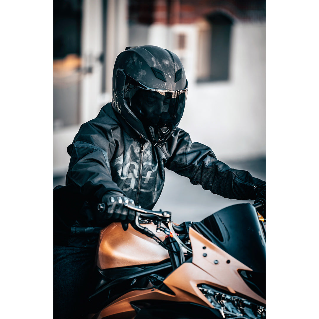 ICON Airflite™ Demo MIPS® Helmet Black - Lifestyle of Rider Wearing Helmet while Riding Orange Motorcycle