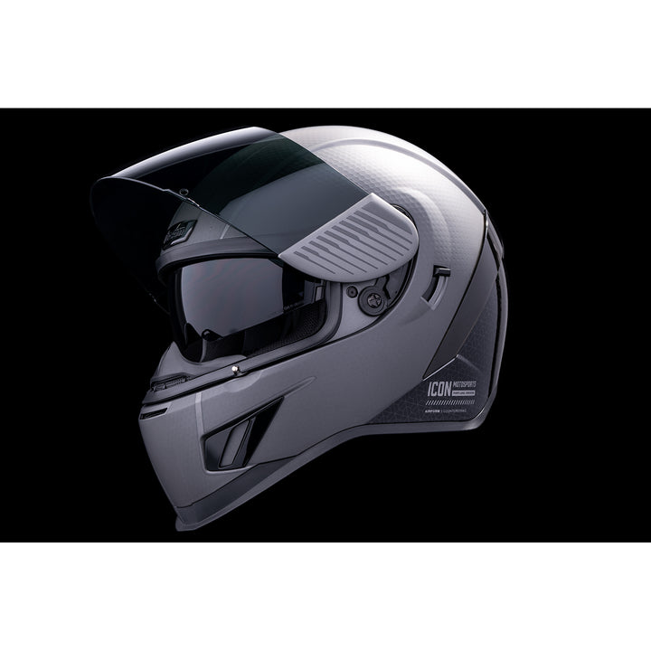 ICON Airform™ Counterstrike MIPS® Helmet Silver - Front Left Side View with Dark Studio Background, Faceshield Raised, and Drop Down Sun Visor Lowered