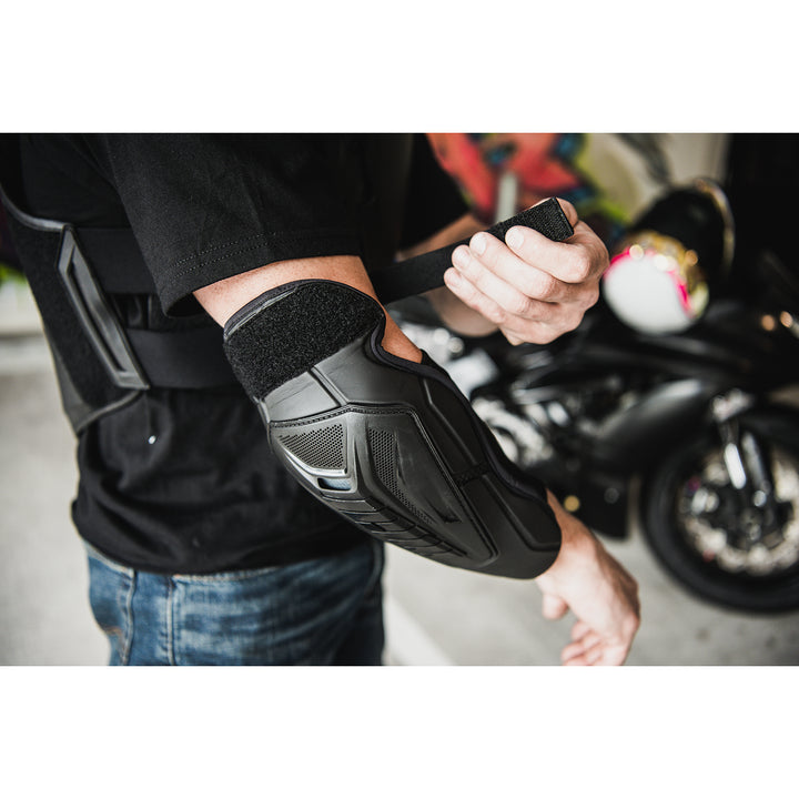 ICON Field Armor 3™ Elbows Black - Lifestyle Close-Up of Rider Putting on Elbow armor